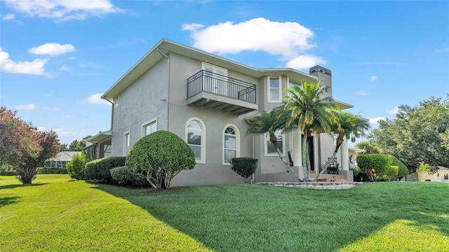 rear view of property with a balcony and a lawn