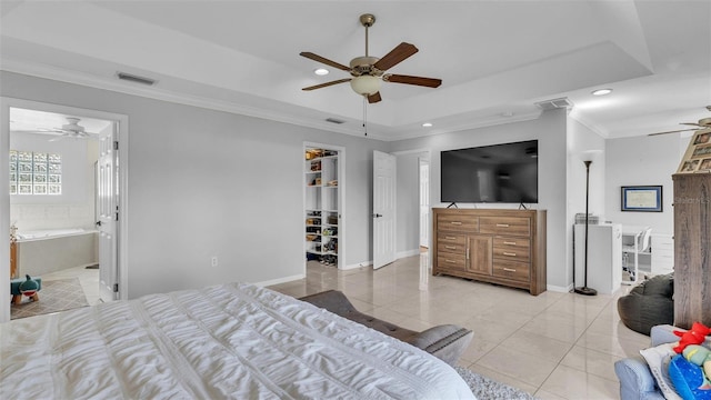 bedroom with crown molding, a walk in closet, light tile patterned floors, a tray ceiling, and ceiling fan