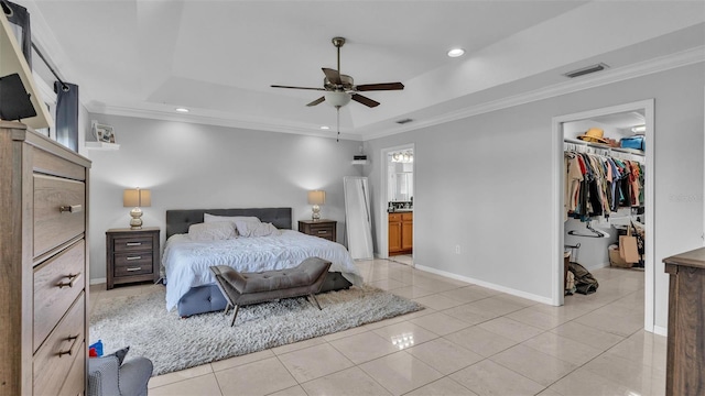 tiled bedroom with a spacious closet, a tray ceiling, crown molding, ensuite bath, and a closet