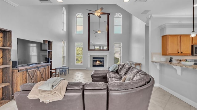 living room featuring crown molding, ceiling fan, a towering ceiling, and light tile patterned floors