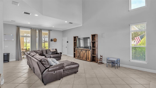 living room with light tile patterned flooring, crown molding, and a high ceiling