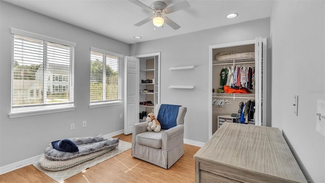 living area with wood-type flooring and ceiling fan