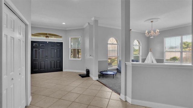 tiled foyer with a notable chandelier, crown molding, and a wealth of natural light