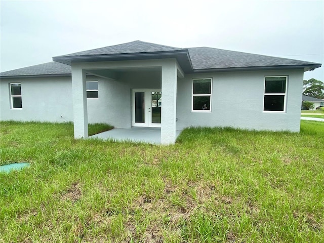 rear view of property with french doors, a yard, stucco siding, and a shingled roof