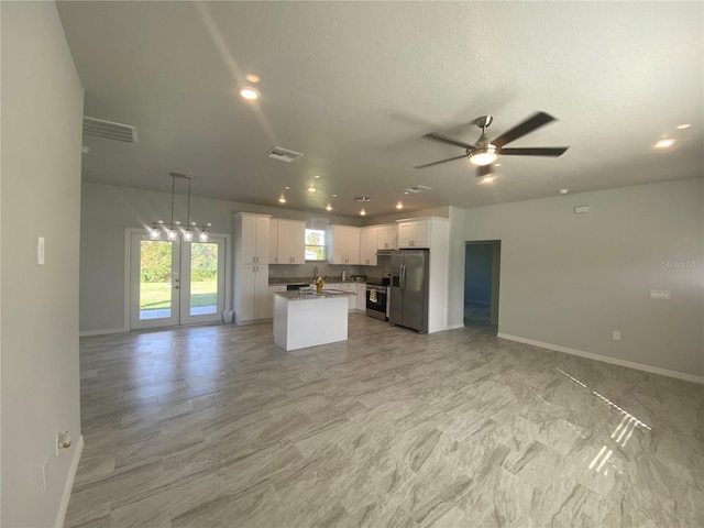 kitchen featuring a center island, white cabinetry, ceiling fan, stainless steel appliances, and decorative light fixtures