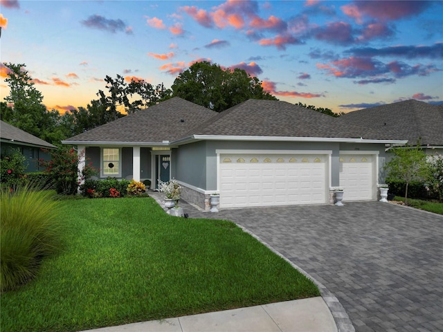 ranch-style house featuring a garage and a lawn