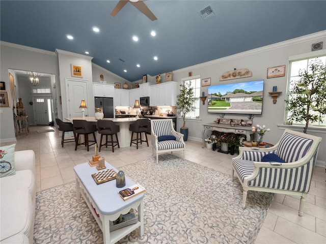 living room with a healthy amount of sunlight, vaulted ceiling, light tile patterned flooring, and ceiling fan with notable chandelier