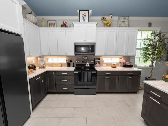 kitchen with light tile patterned flooring, ornamental molding, stainless steel appliances, and white cabinetry