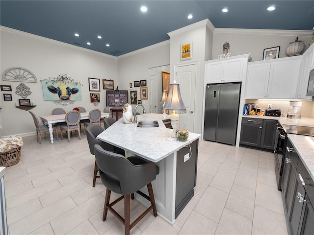 kitchen featuring white cabinets, black appliances, sink, ornamental molding, and a kitchen island with sink