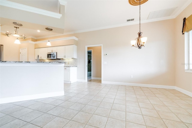 kitchen with light stone counters, tasteful backsplash, ornamental molding, and white cabinets