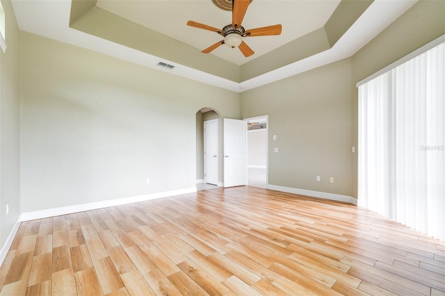 unfurnished room with ceiling fan, a raised ceiling, and light hardwood / wood-style floors