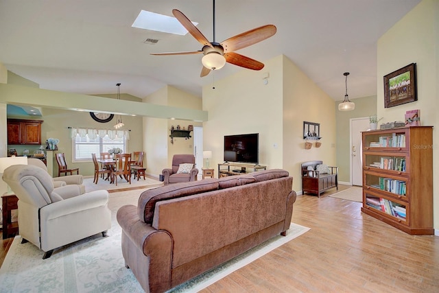 living room featuring a skylight, high vaulted ceiling, ceiling fan, and hardwood / wood-style floors