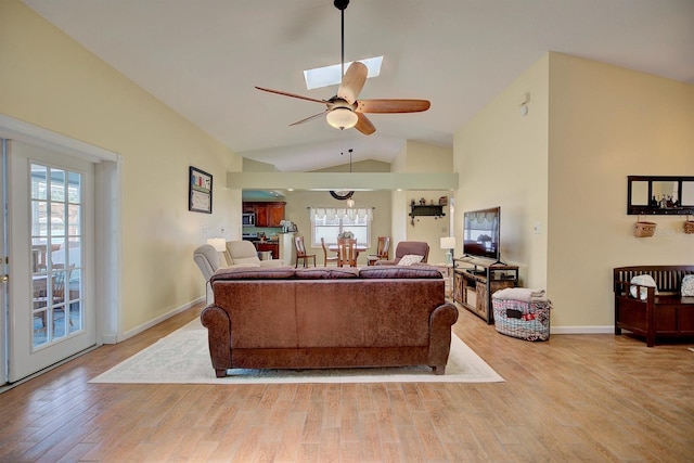 living room featuring ceiling fan, hardwood / wood-style flooring, a skylight, and high vaulted ceiling