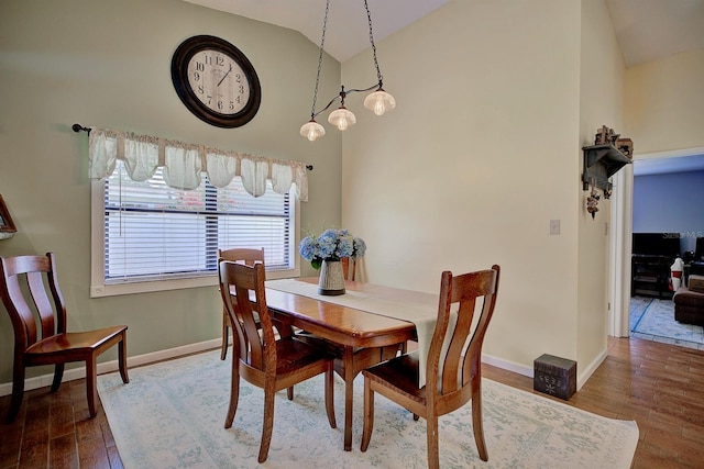 dining space with high vaulted ceiling and hardwood / wood-style floors