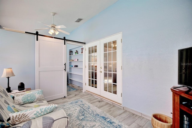 sitting room featuring a barn door, french doors, ceiling fan, and light hardwood / wood-style floors