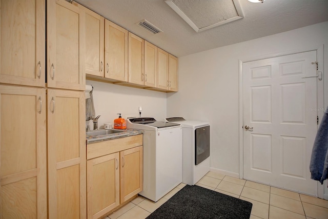 laundry area featuring washer and clothes dryer, sink, cabinets, and light tile patterned floors