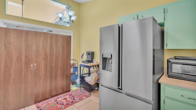 kitchen featuring pendant lighting, stainless steel fridge, light tile patterned floors, green cabinetry, and a chandelier