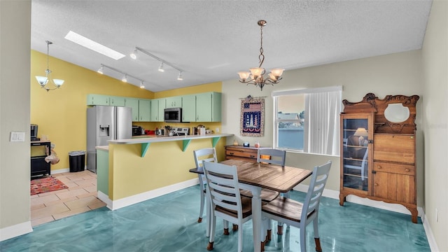 dining room featuring a skylight, a chandelier, tile patterned floors, and a textured ceiling