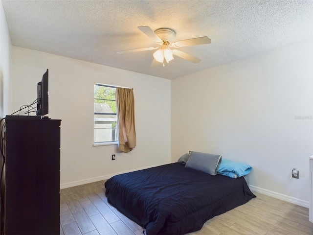 bedroom featuring ceiling fan, light hardwood / wood-style flooring, and a textured ceiling