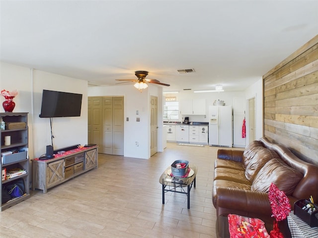 living room with ceiling fan and wooden walls