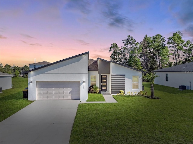 contemporary home with a garage, central AC unit, and a lawn