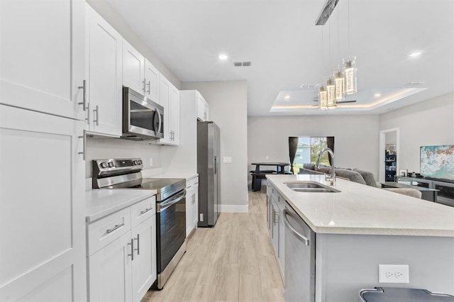 kitchen featuring white cabinetry, sink, stainless steel appliances, and a center island with sink