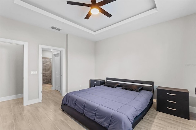 bedroom with ceiling fan and a tray ceiling