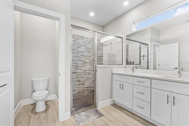 bathroom with a shower with door, vanity, hardwood / wood-style flooring, and toilet