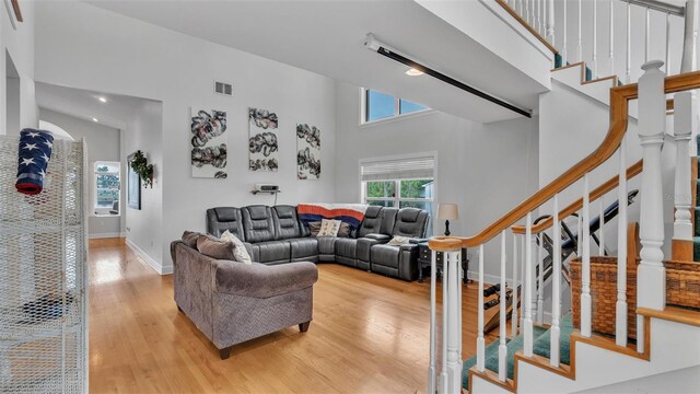 living room with high vaulted ceiling and light wood-type flooring