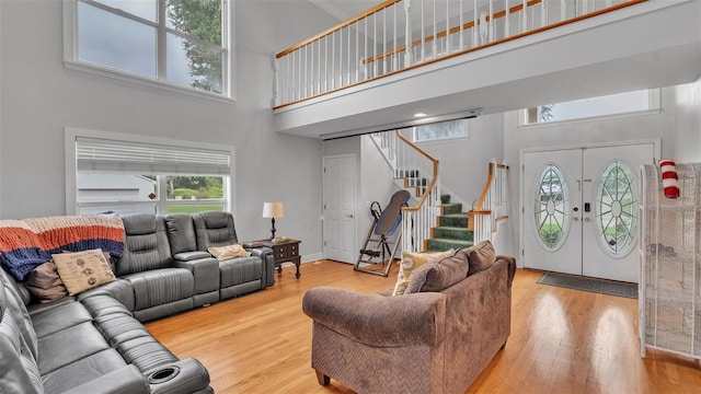 living room featuring light hardwood / wood-style floors, french doors, and a towering ceiling