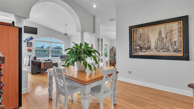 dining area with decorative columns, light wood-type flooring, ceiling fan, and lofted ceiling