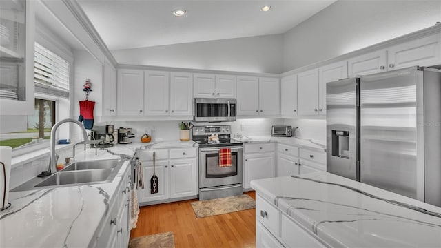 kitchen featuring white cabinetry, decorative backsplash, light hardwood / wood-style floors, appliances with stainless steel finishes, and lofted ceiling