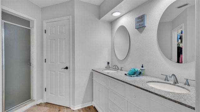 bathroom featuring hardwood / wood-style floors, walk in shower, and dual bowl vanity