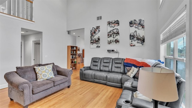 living room featuring a towering ceiling and light hardwood / wood-style flooring