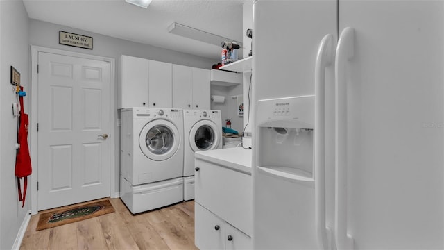 laundry room with washing machine and clothes dryer, cabinets, and light hardwood / wood-style floors