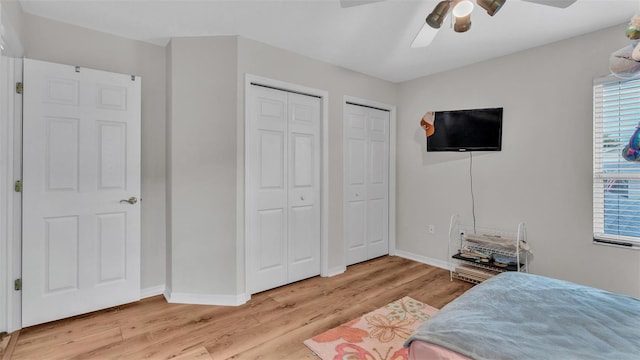 bedroom with light hardwood / wood-style floors, multiple closets, and ceiling fan