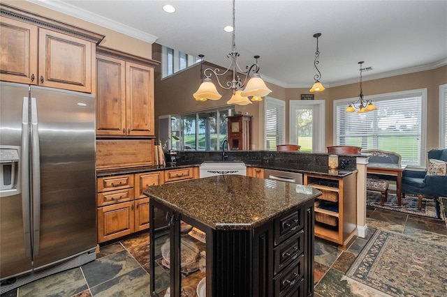 kitchen with ornamental molding, a sink, stone tile floors, stainless steel appliances, and an inviting chandelier