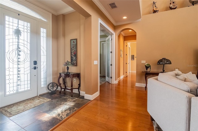 foyer entrance featuring visible vents, baseboards, ornamental molding, wood finished floors, and arched walkways