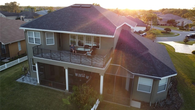 back of property featuring stucco siding, a lawn, and roof with shingles
