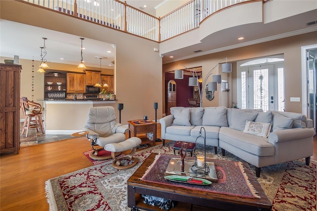 living room featuring visible vents, ornamental molding, recessed lighting, a high ceiling, and wood finished floors