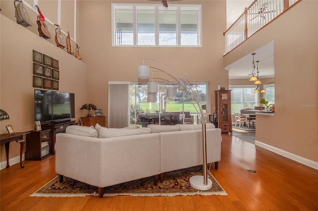 living area with a high ceiling, wood finished floors, and baseboards