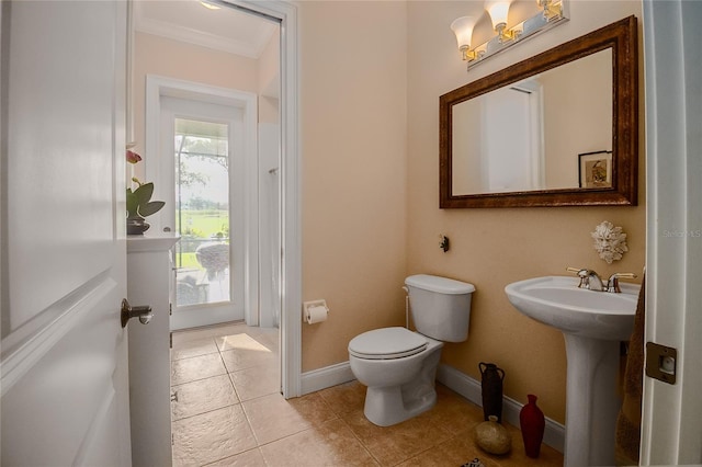 bathroom with baseboards, toilet, ornamental molding, tile patterned floors, and a sink