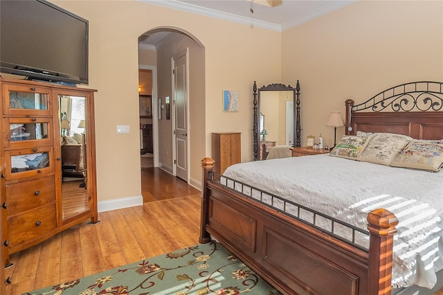 bedroom featuring arched walkways, baseboards, light wood-style floors, and ornamental molding