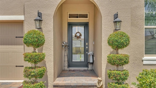 entrance to property with a garage and stucco siding