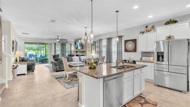 kitchen featuring white cabinetry, stainless steel appliances, a sink, and open floor plan