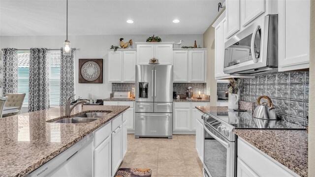 kitchen featuring a sink, white cabinetry, appliances with stainless steel finishes, light stone countertops, and tasteful backsplash