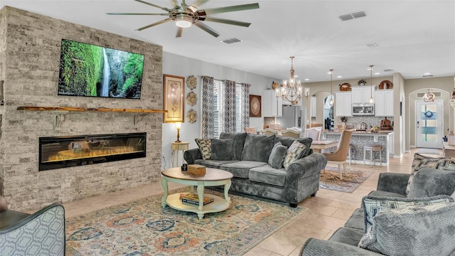 living area featuring arched walkways, ceiling fan with notable chandelier, a fireplace, and visible vents