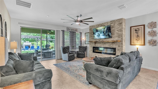 living room with baseboards, visible vents, a ceiling fan, and a stone fireplace