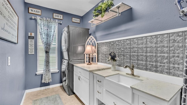 bathroom with stacked washing maching and dryer, tile patterned floors, vanity, and baseboards