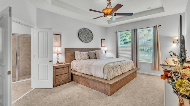 bedroom with light carpet, ceiling fan, and a tray ceiling